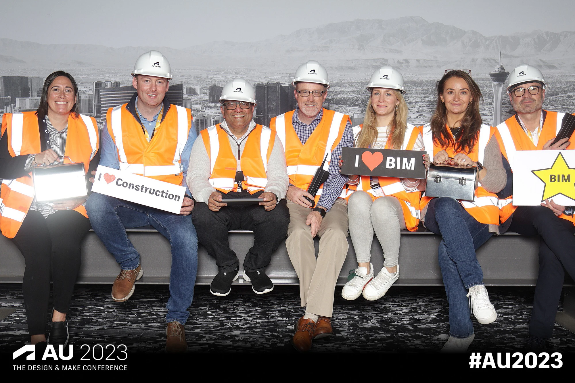 Six on the girder in hard hats with an I love BIM sign at Autodesk University 2023