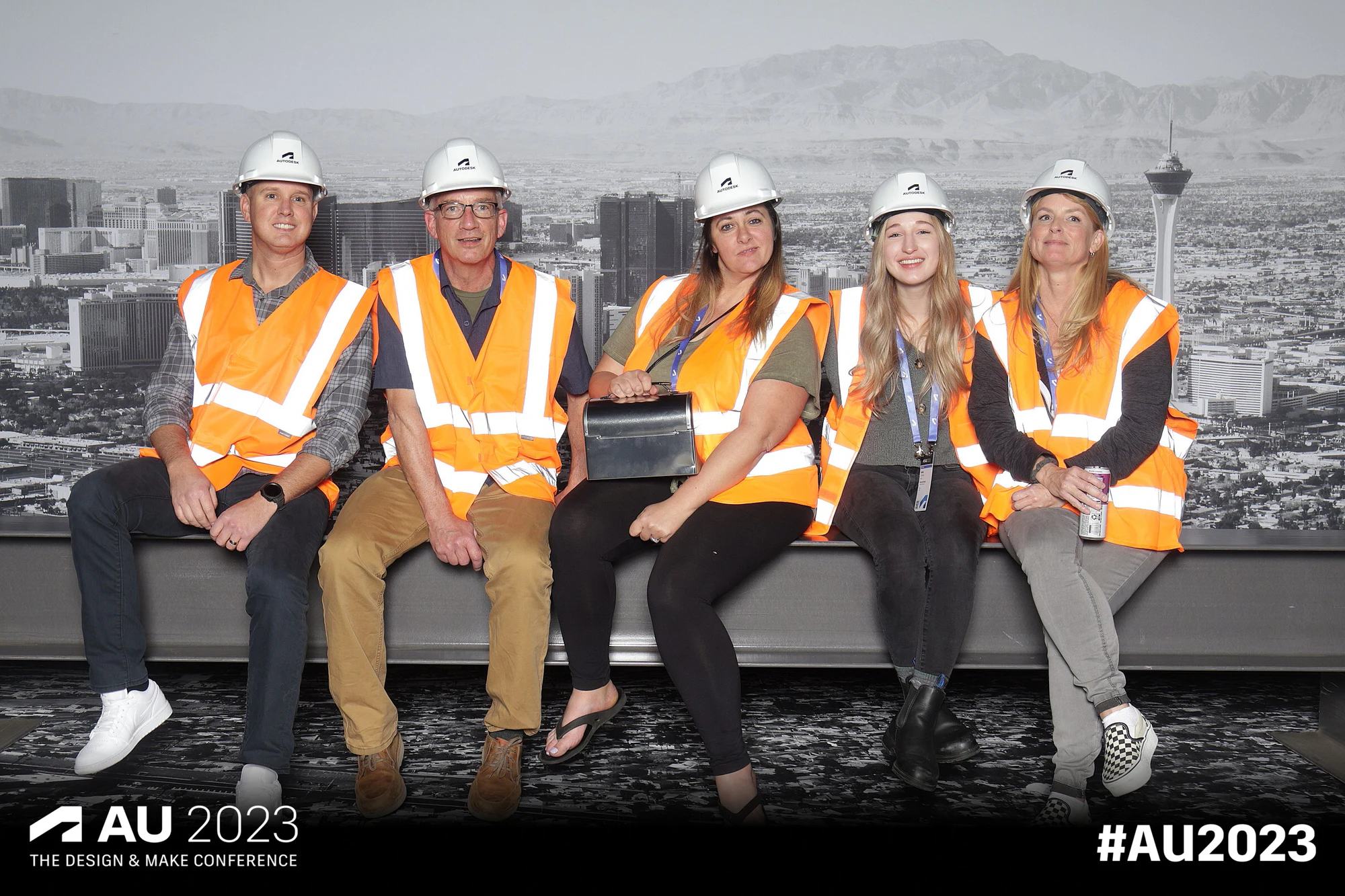 Five seated in a row on the girder, the Vegas skyline behind at Autodesk University 2023