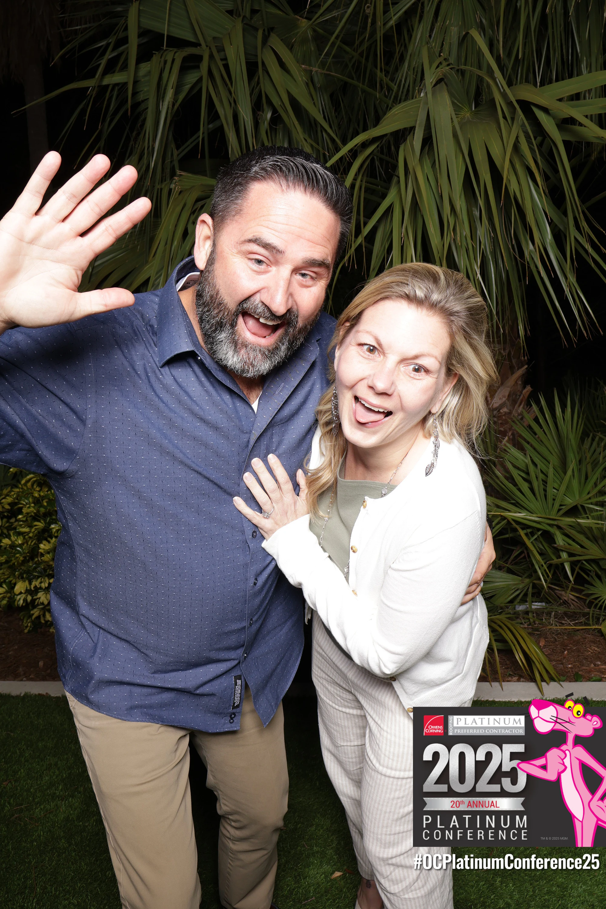 Couple at the booth, man mid-wave with a huge grin, at the Owens Corning Platinum Conference 2025