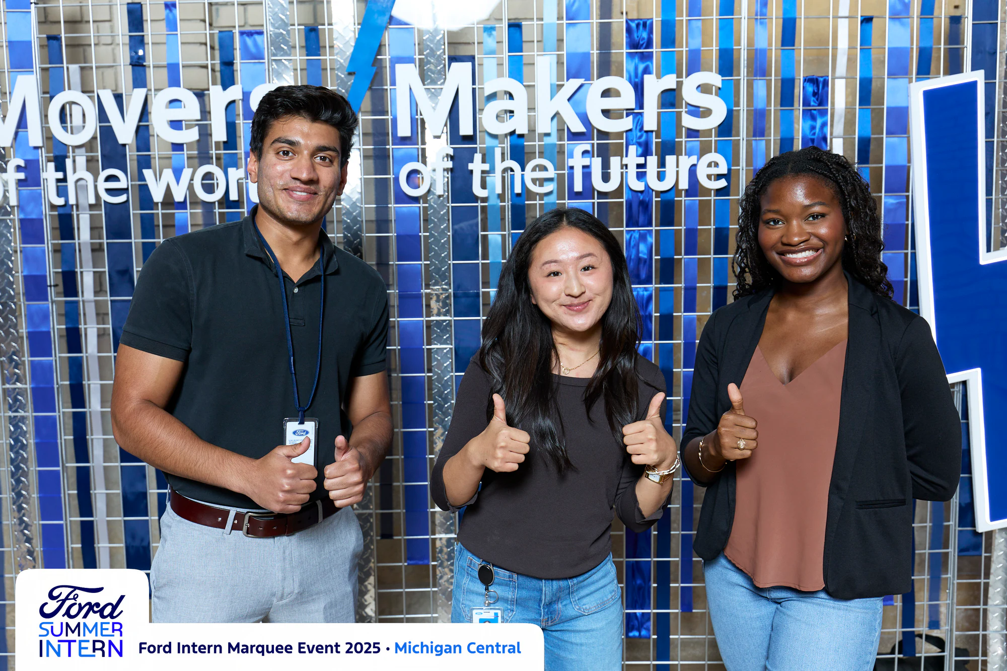 Three interns, thumbs up, easy energy against the blue set
