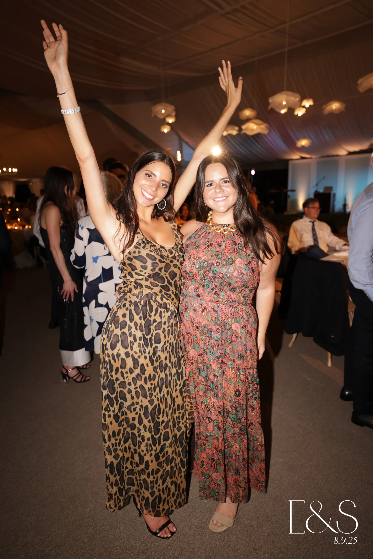 Two guests throwing their arms up under the tent lights at Emmy + Shelby at Franklin Hills Country Club