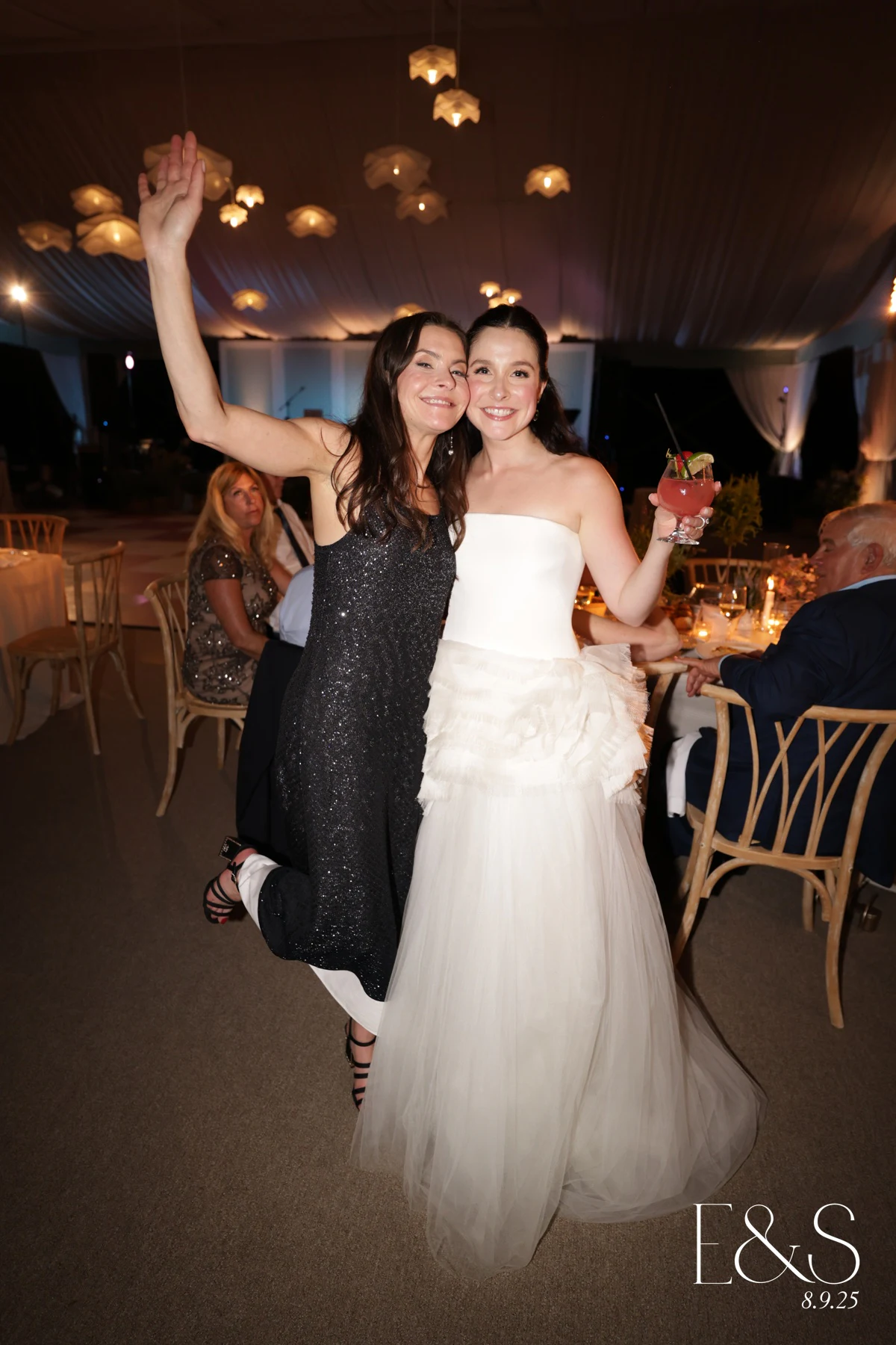 Bride with a friend, one arm in the air, at Emmy + Shelby at Franklin Hills Country Club