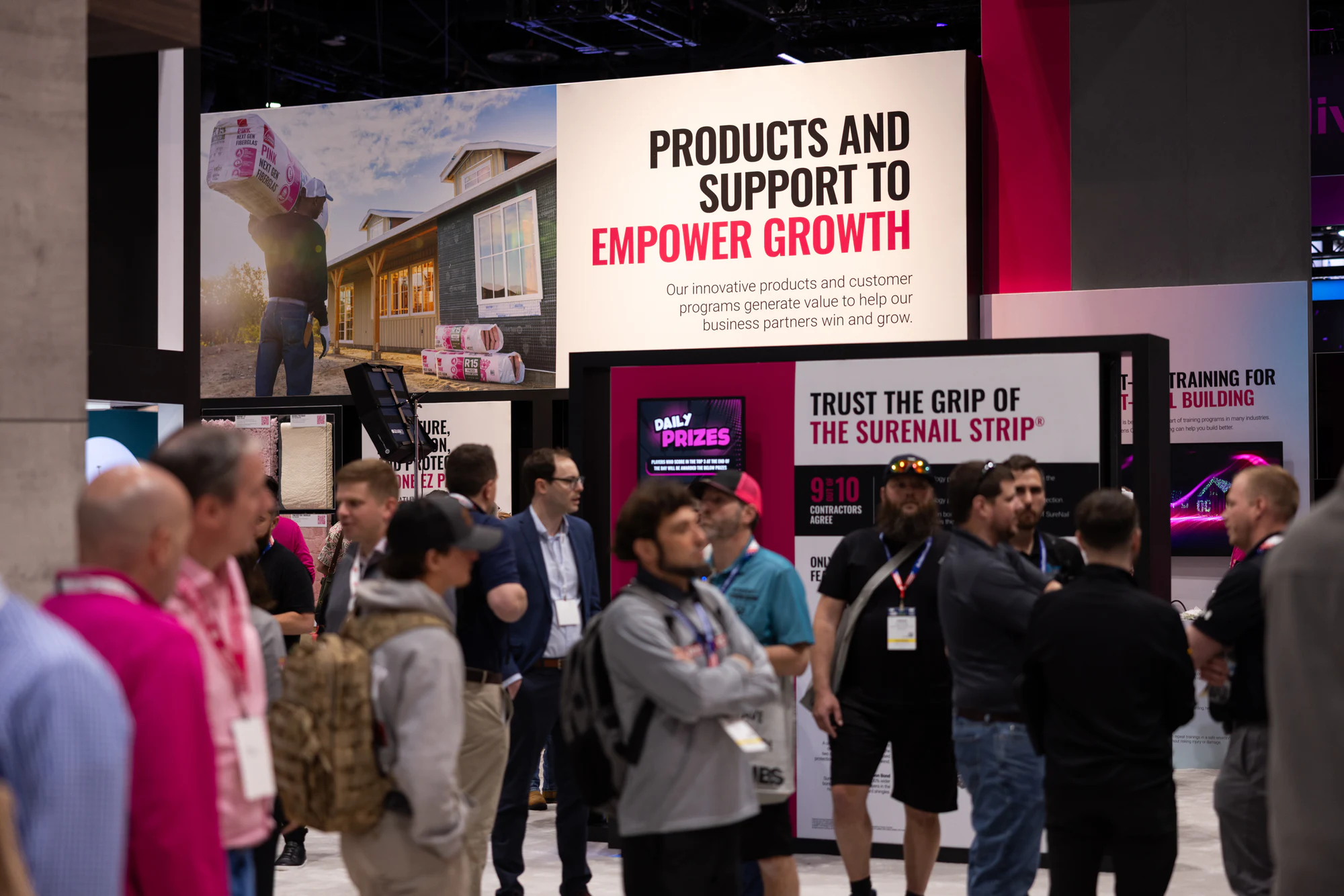 Cluster of attendees watching the SureNail Grip screen at Owens Corning at IBS 2026