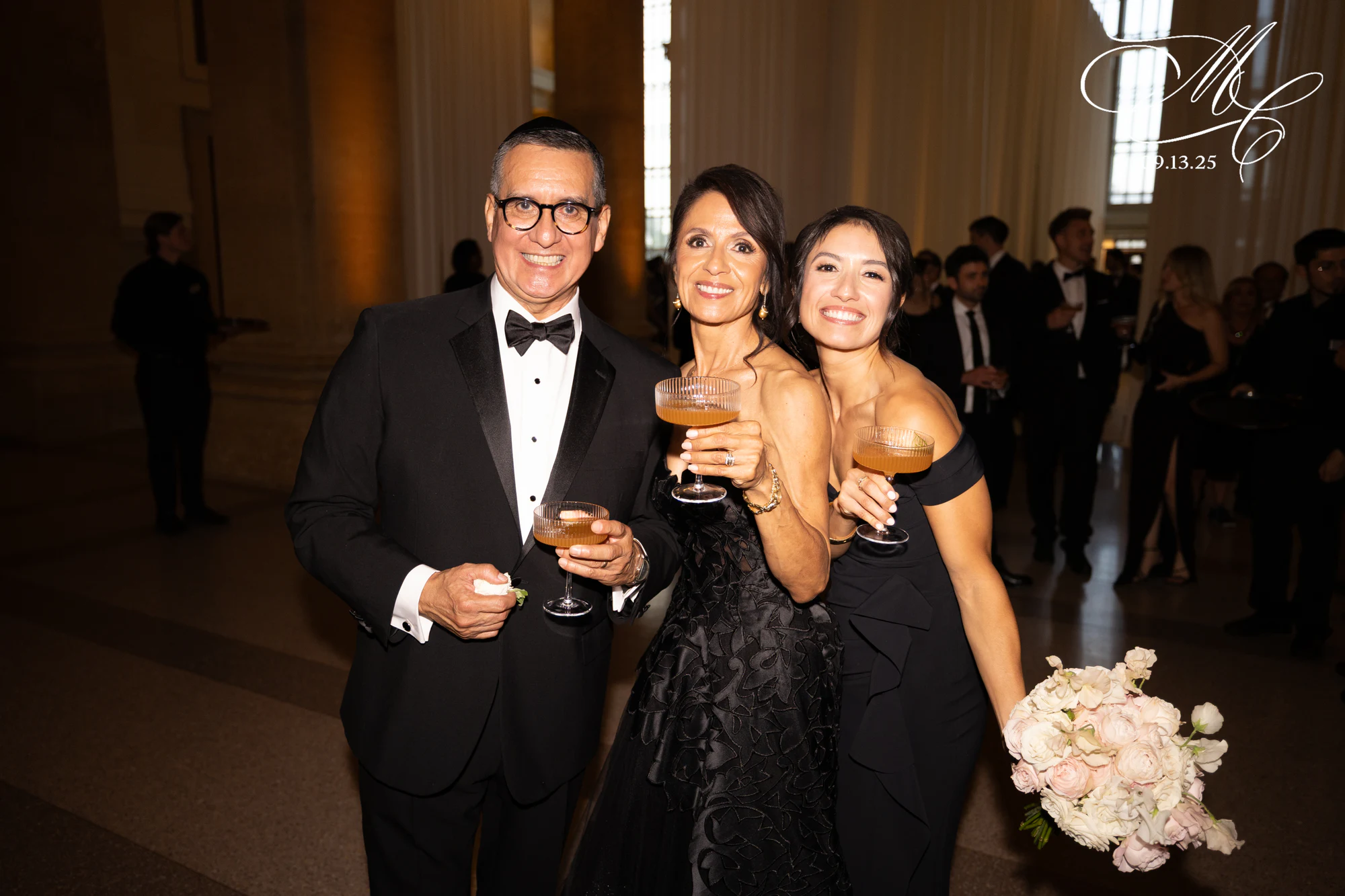 Three guests laughing with drinks at Madison + Charlie's wedding at Michigan Central